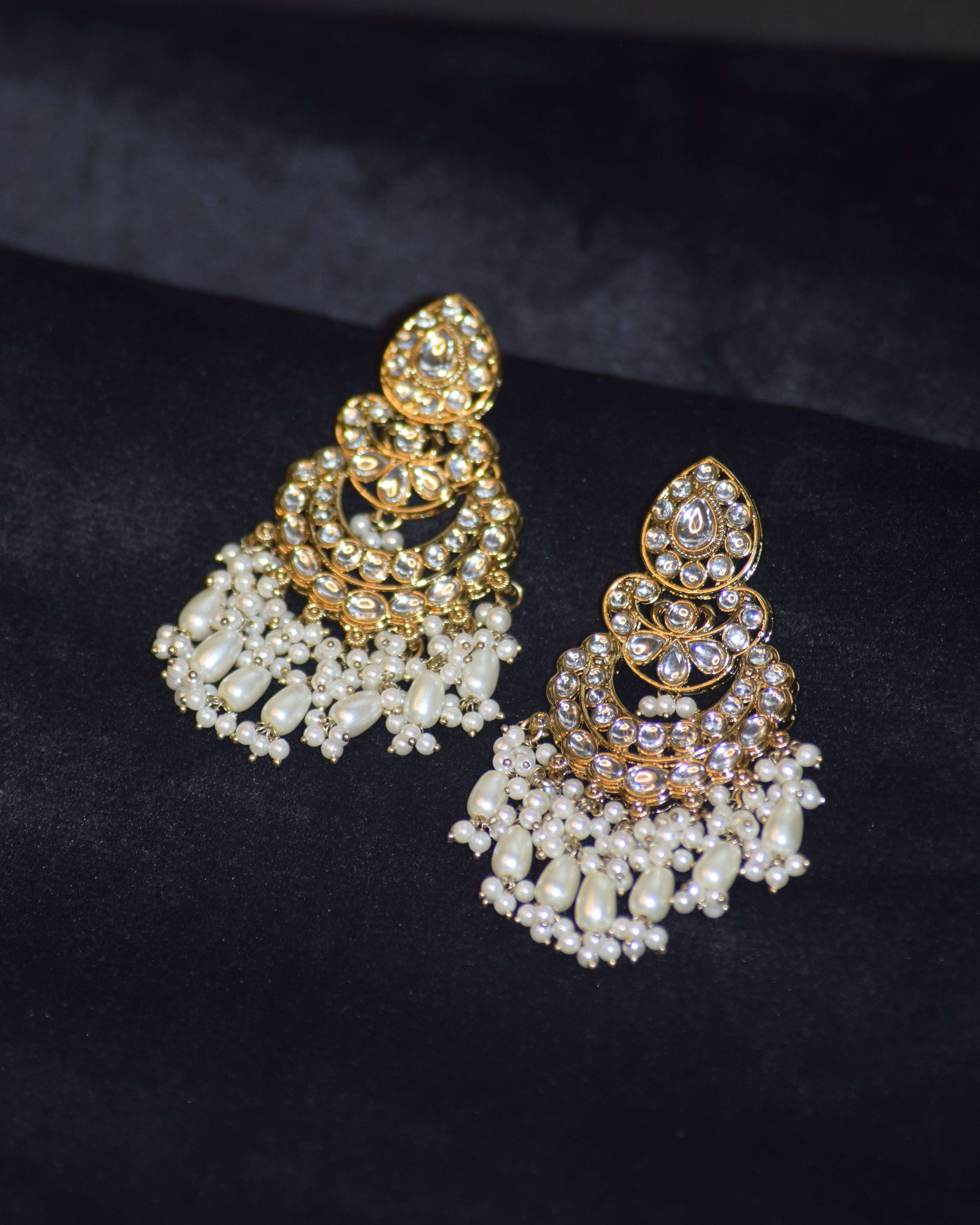 Pair of gold and pearl earrings on a black background
