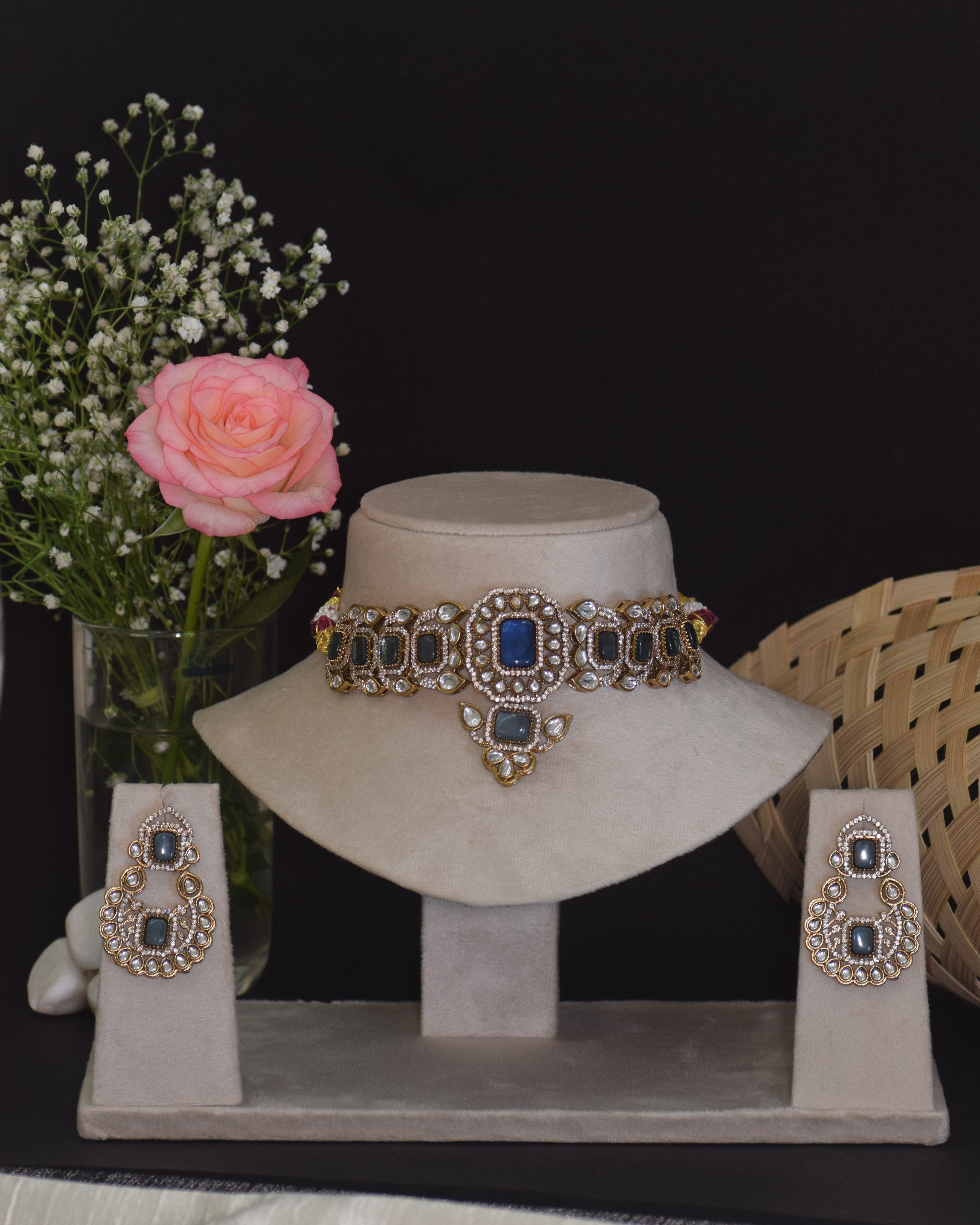 Jewelry set with necklace and earrings on a stand, accompanied by flowers and a basket.