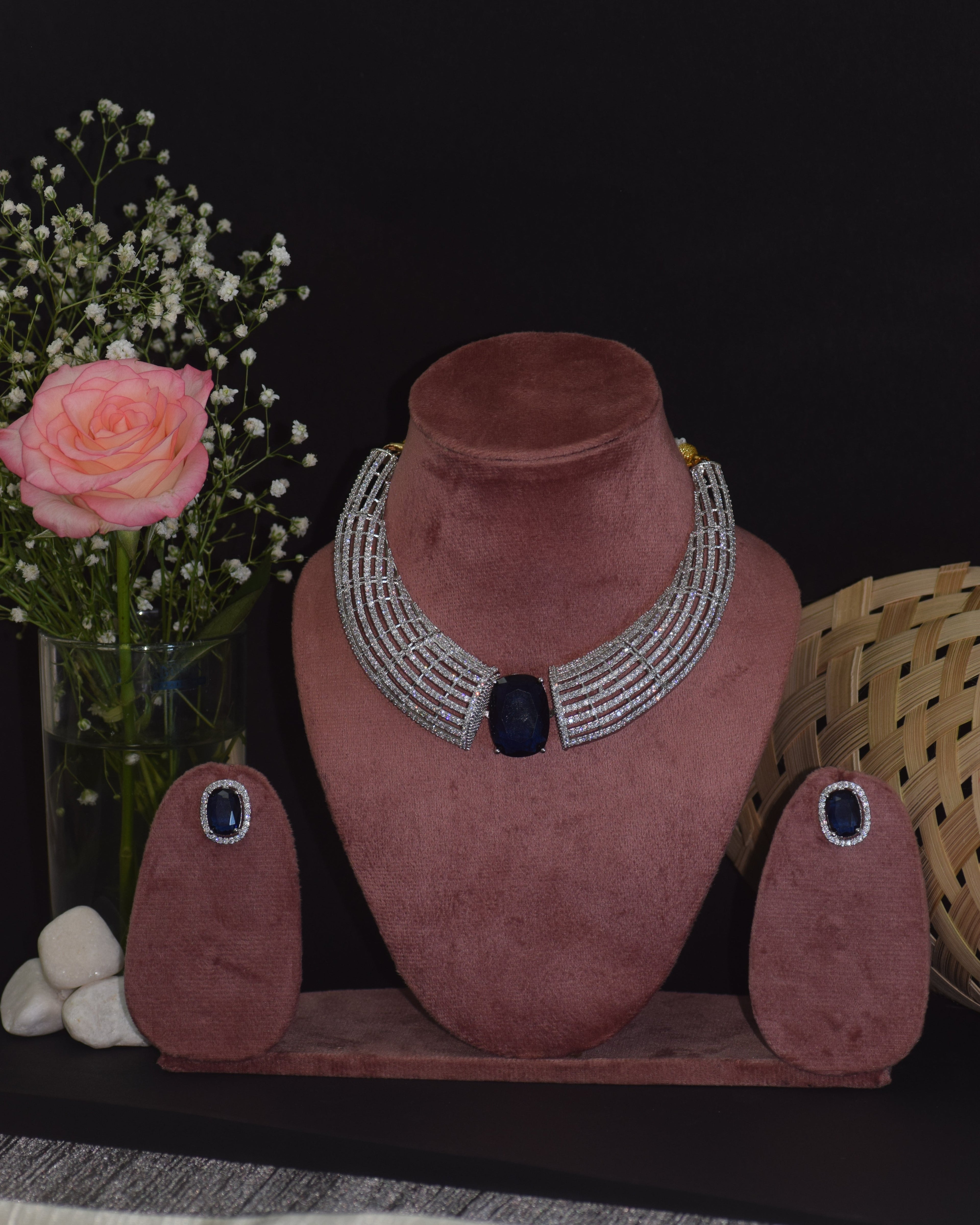 Pink jewelry display with necklaces and a rose on a dark surface