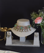 Decorative bracelet on a white stand with flowers in the background