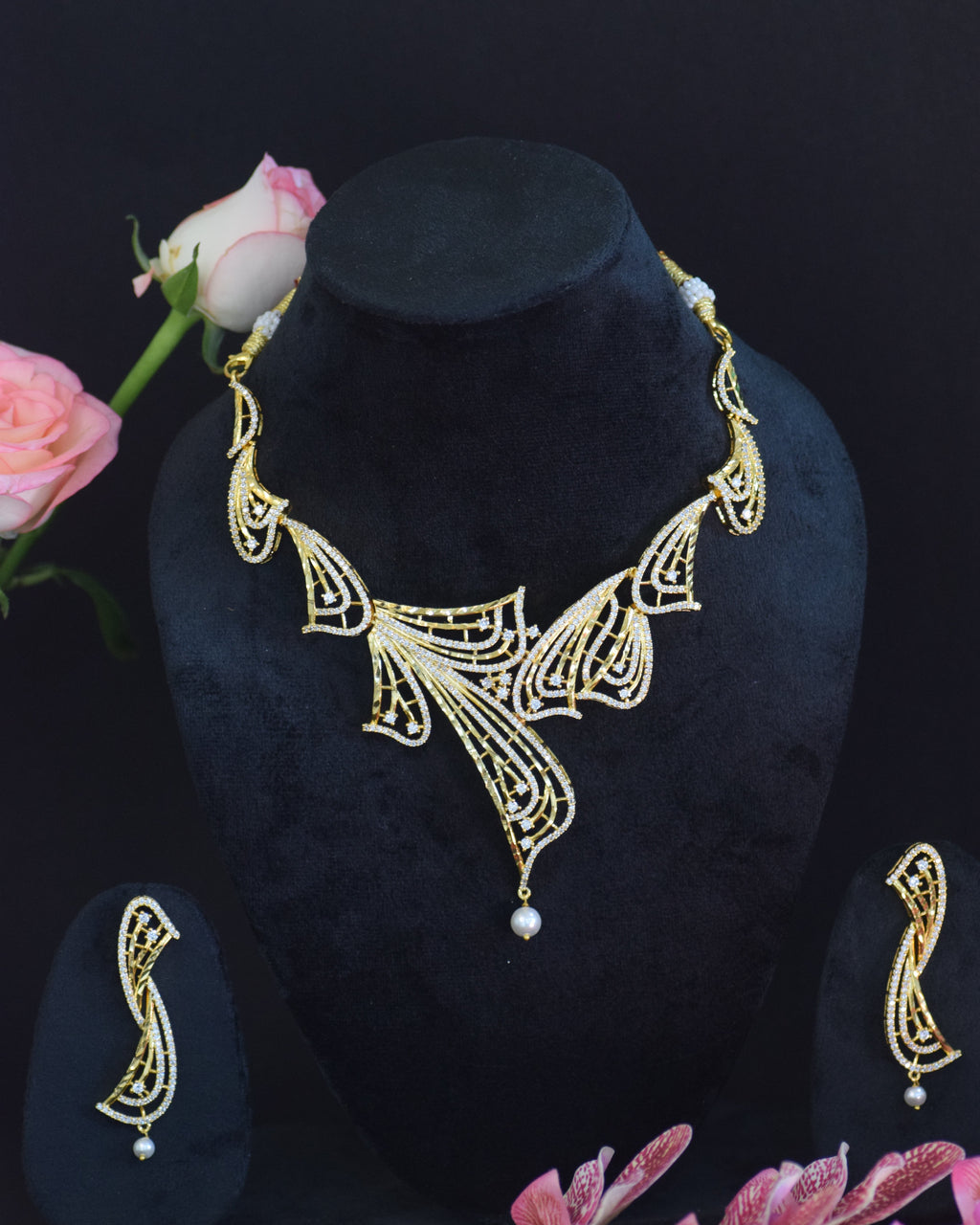 Decorative gold headband with floral design on a black background with pink flowers.