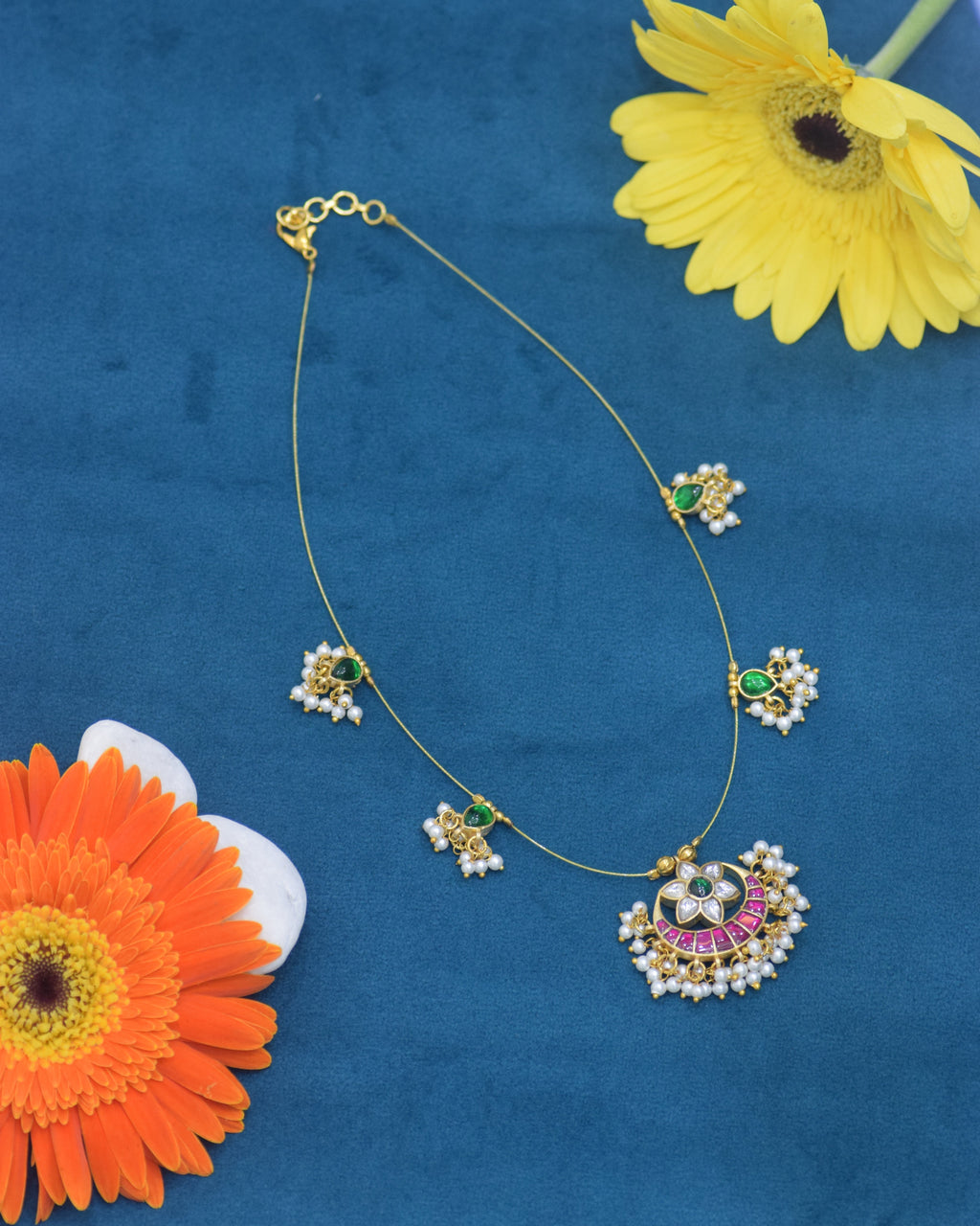 Necklace with floral pendants on a blue background with flowers
