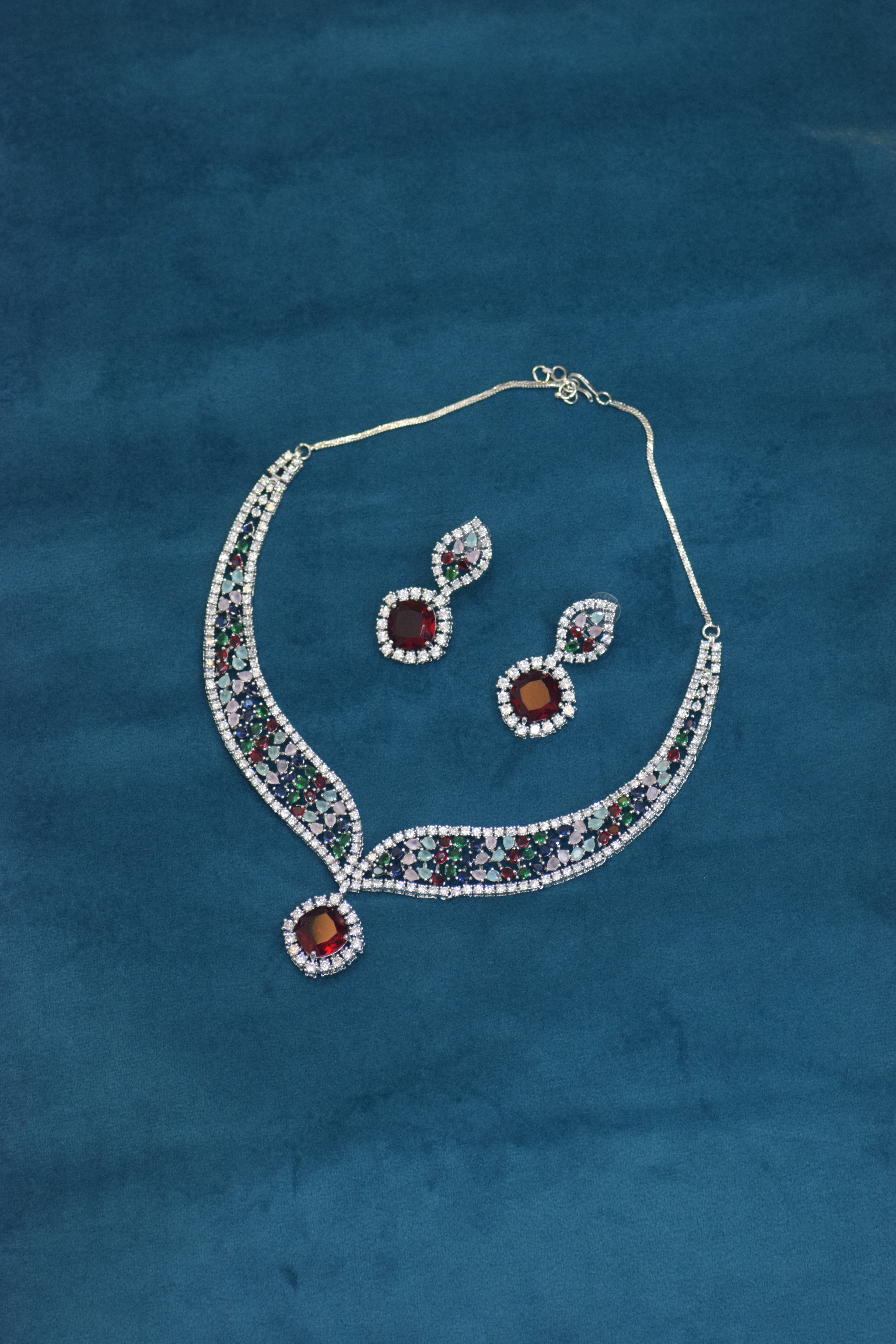 Jewelry set with necklace and earrings on a blue fabric background