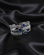 Two silver rings with blue gemstones on black satin fabric