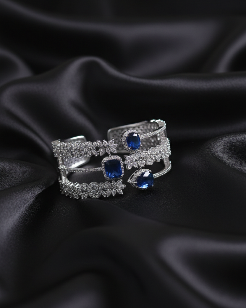 Two silver rings with blue gemstones on black satin fabric