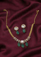 Gold necklace with green gemstones on a maroon fabric background