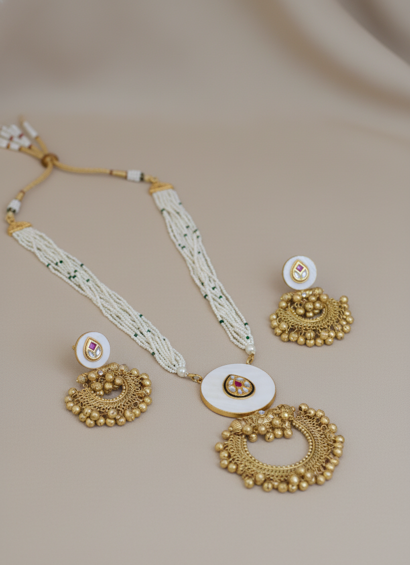 Gold jewelry set with necklace and earrings on a beige background