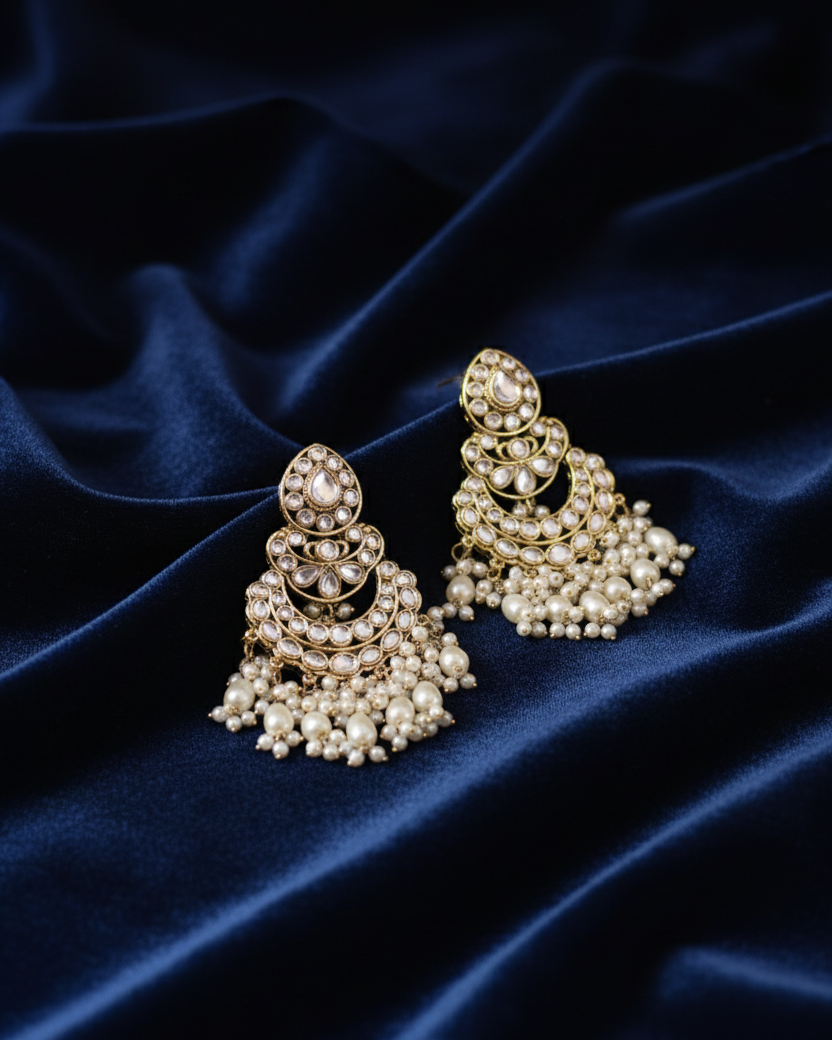 Pair of pearl earrings on a dark blue satin background