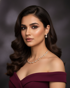 Woman wearing a burgundy off-shoulder dress with jewelry against a dark background