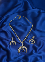 Gold necklace and earrings on a blue fabric background