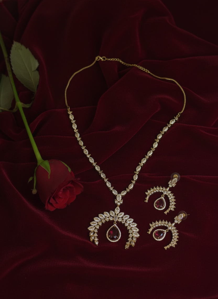 Gold jewelry set with necklace and earrings on a dark red fabric background