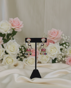 Pair of earrings on a stand with flowers in the background