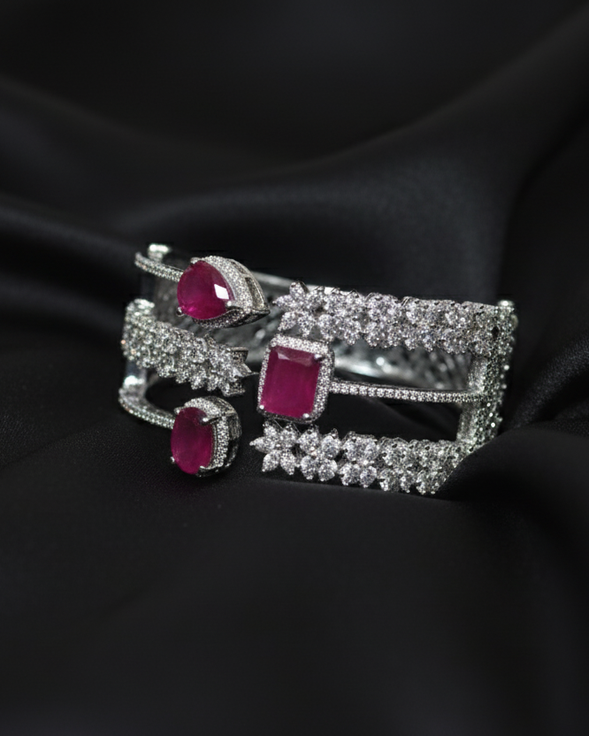 Silver bracelet with red gemstones on a black fabric background