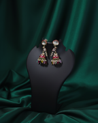 Earrings on a black stand against a green satin background