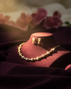 Gold necklace on a red velvet stand with blurred floral background