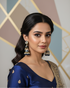 Woman wearing a blue saree with gold details against a geometric patterned wall.