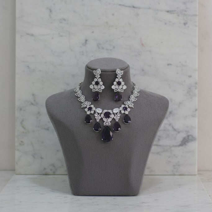 Jewelry set with necklace and earrings on a gray mannequin bust against a marble background