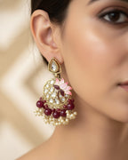 Close-up of a woman wearing a decorative earring with floral design and beads.
