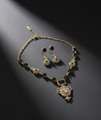 Gold necklace with black and clear gemstones on a dark gray background