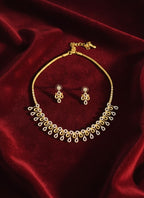 Gold necklace and earrings set on a red velvet background