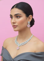 Woman wearing a diamond necklace and earrings on a pink background