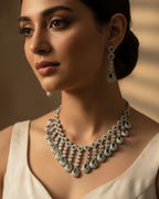 Woman wearing a luxurious diamond and emerald necklace with a neutral background
