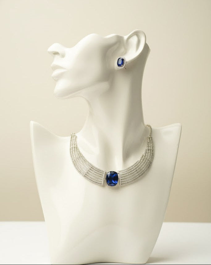 Necklace with blue stones on a white mannequin bust against a beige background