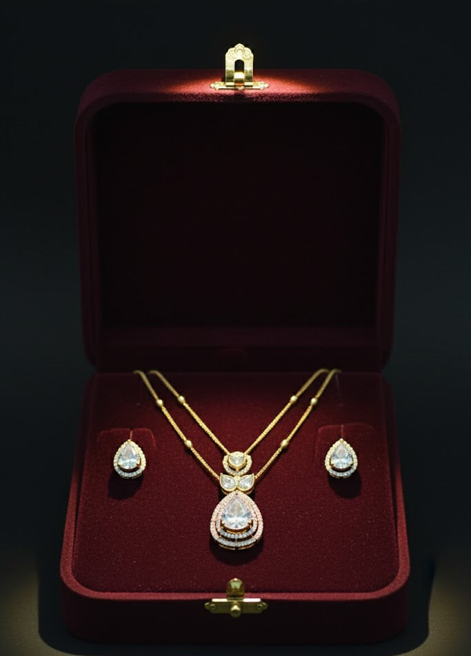 Gold necklace and earrings set in a red jewelry box on a dark background