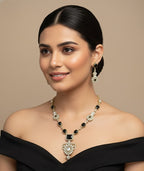 Woman wearing a black off-shoulder top and elegant jewelry on a beige background