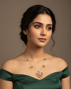 Woman wearing a green off-shoulder top and gold jewelry against a brown background