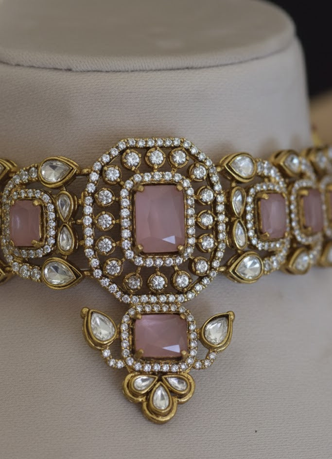 Ornate jewelry piece with pink stones and gold accents on a neutral background