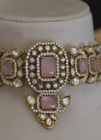 Ornate jewelry piece with pink stones and gold accents on a neutral background