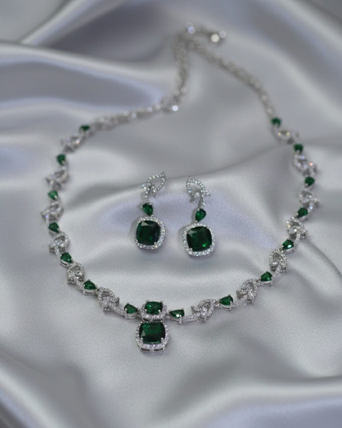 Jewelry set with necklace and earrings featuring green gemstones on a satin background