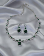 Jewelry set with necklace and earrings featuring green gemstones on a satin background