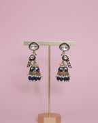 Decorative earrings on a stand against a pink background