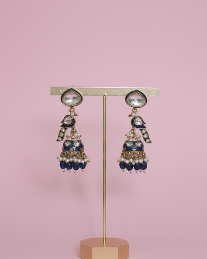 Decorative earrings on a stand against a pink background