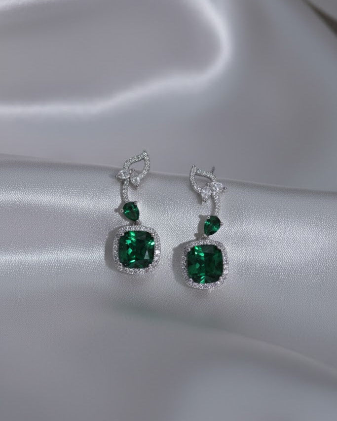 Pair of green gemstone earrings on a satin surface