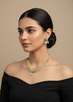 Woman wearing a gold necklace and earrings against a beige background