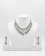 Silver necklace with green stones on a white mannequin bust against a white background