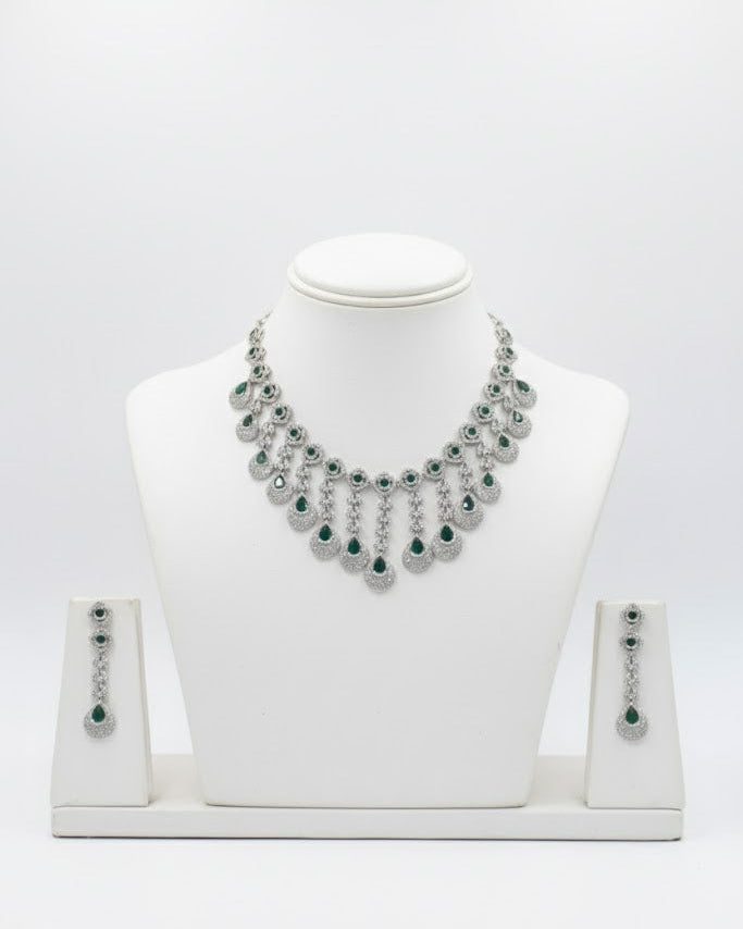 Silver necklace with green stones on a white mannequin bust against a white background