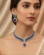 Woman wearing a blue and silver necklace and earrings against a beige background