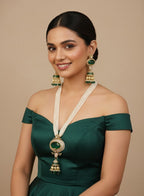Woman wearing a green off-shoulder dress with gold jewelry on a beige background
